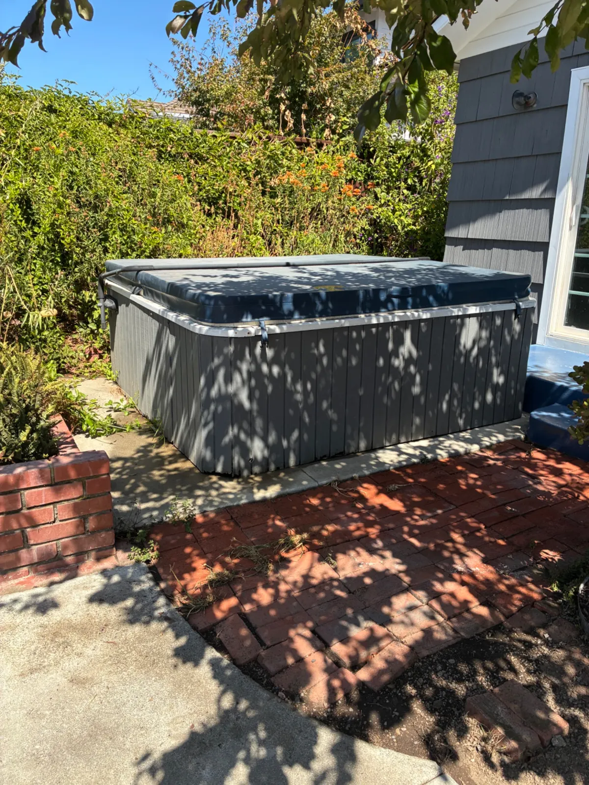 Old hot tub ready for removal in a backyard