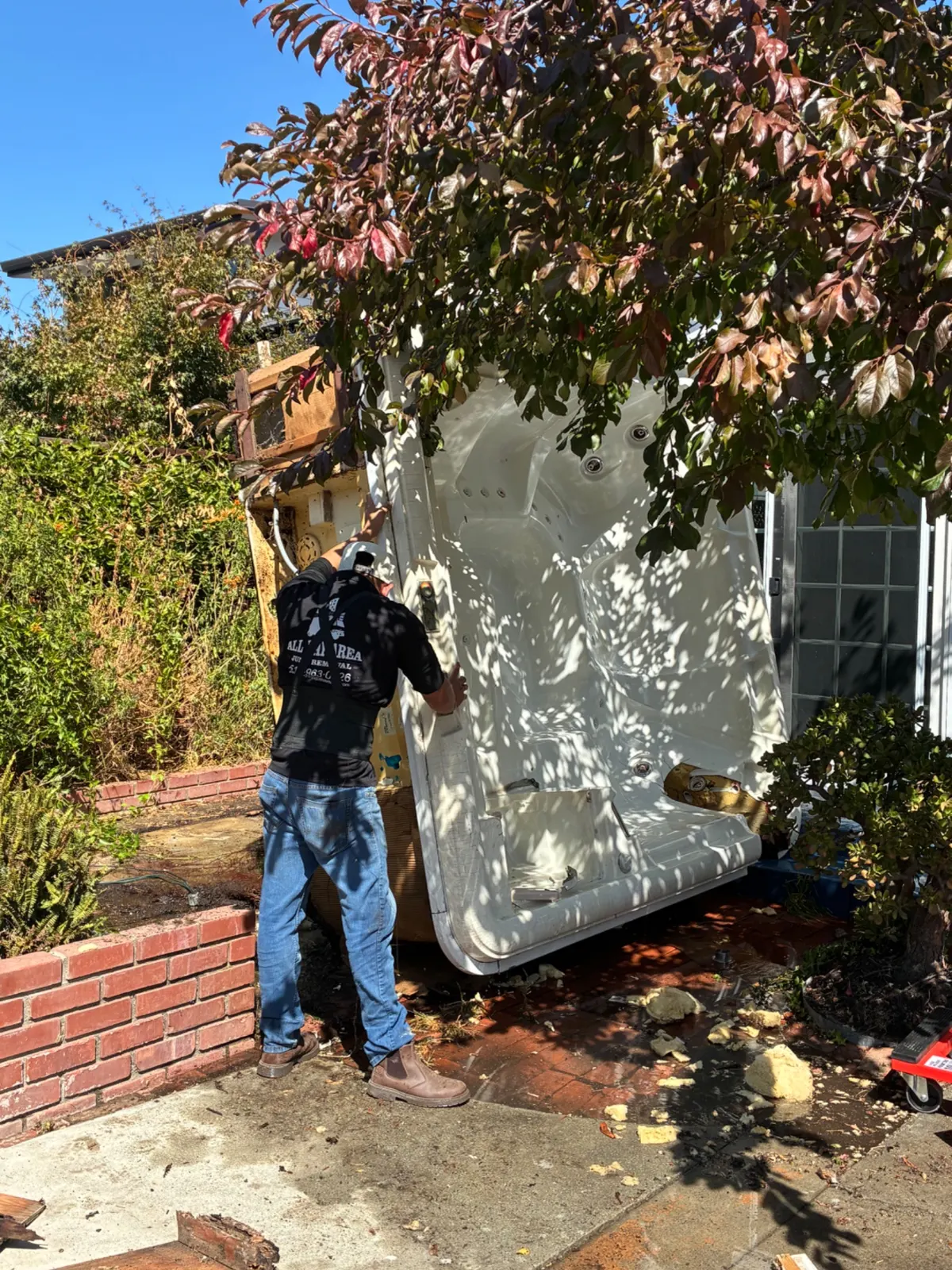 Crew member removing an old hot tub from a backyard