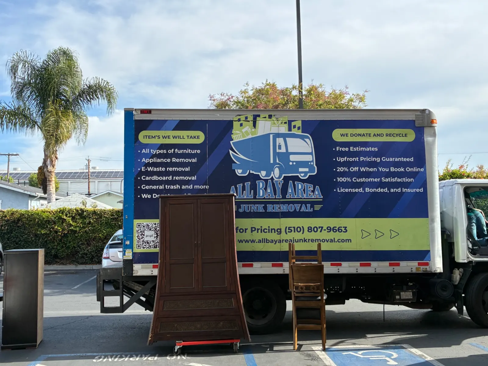 All Bay Area Junk Removal box truck with its branded wrap, loading old furniture